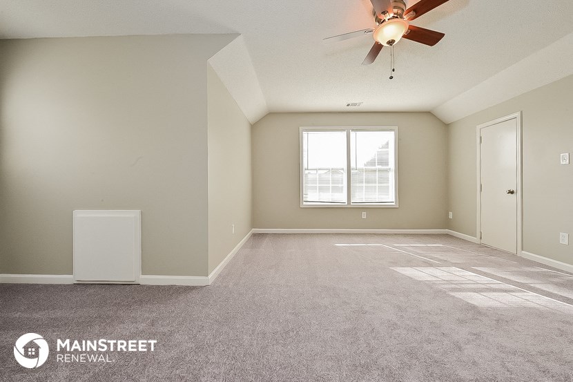 an empty living room with a ceiling fan
