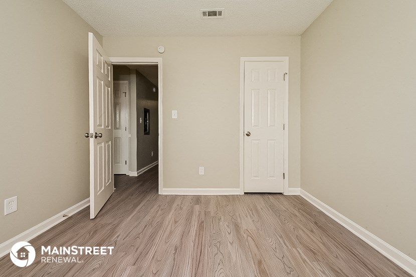 the living room of an apartment with wood floors and a white door