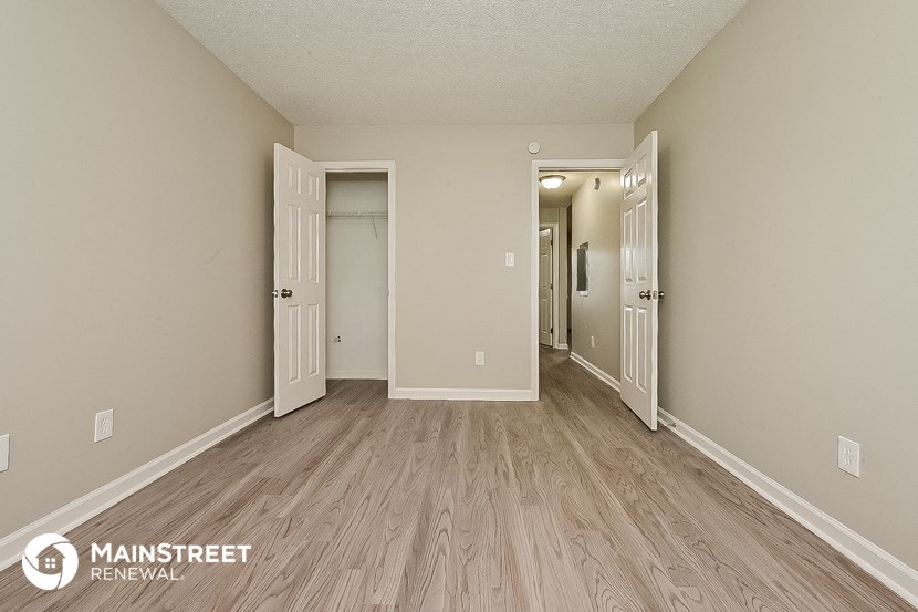 the living room of an apartment with wood floors and white walls