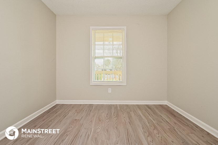 the spacious living room with wood flooring and a window