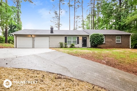 a white and brick house with a driveway and trees