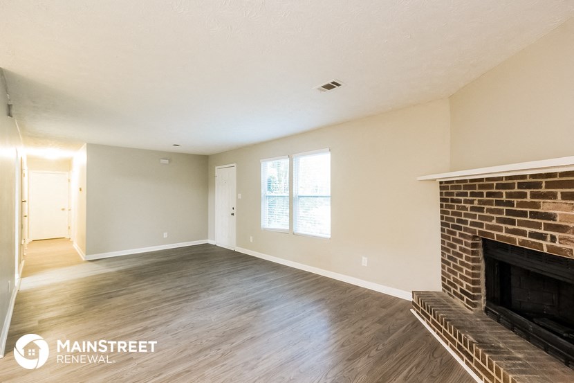 a living room with a brick fireplace and wooden floors