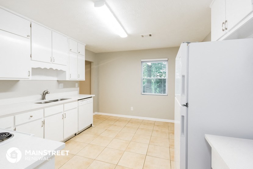 a kitchen with white cabinets and a sink and a refrigerator