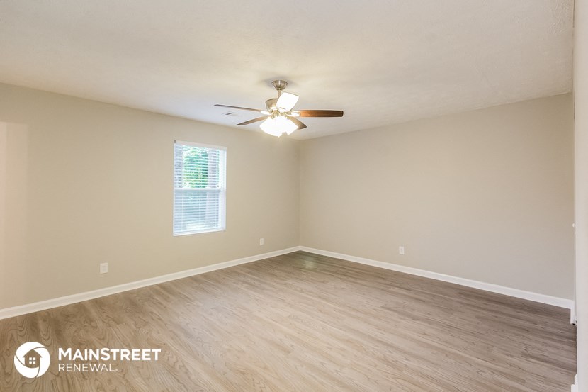 the spacious living room with wood flooring and ceiling fan