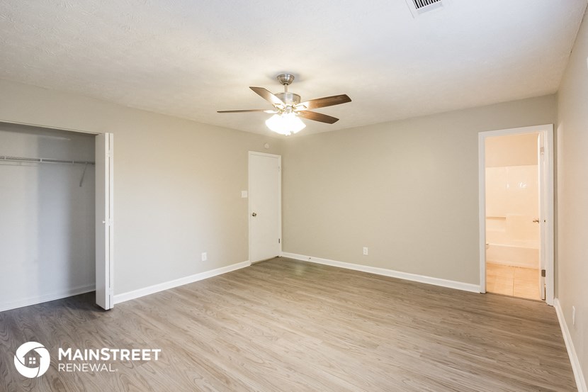 the spacious living room with wood flooring and ceiling fan