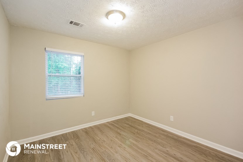 the interior of an empty room with wood flooring and a window