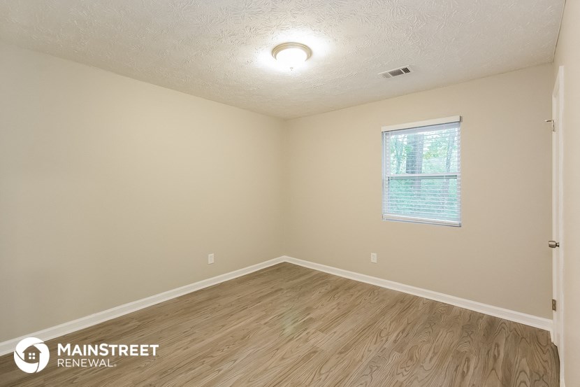 the interior of an empty room with wood flooring and a window