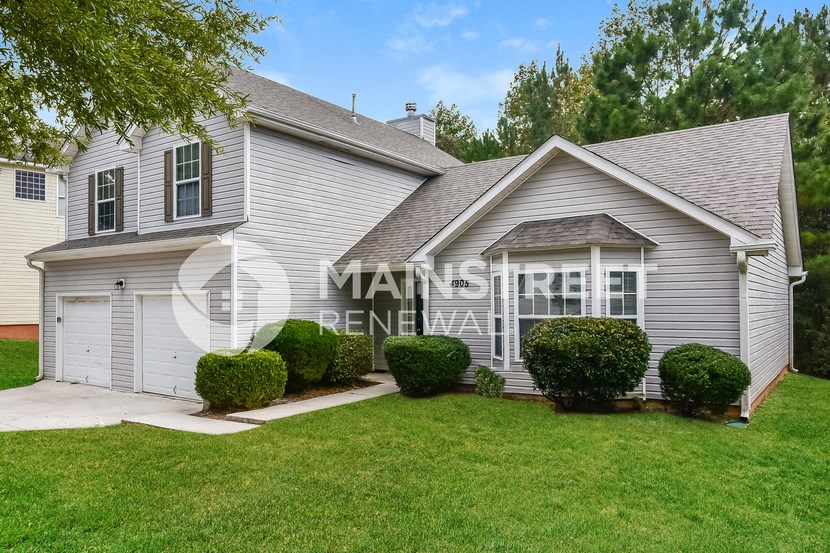 a white house with a garage and a lawn
