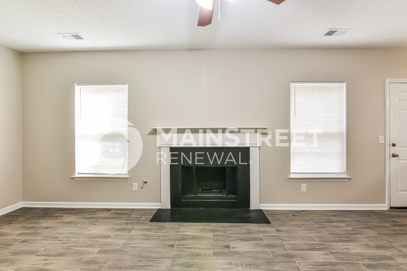 a living room with a fireplace and two windows