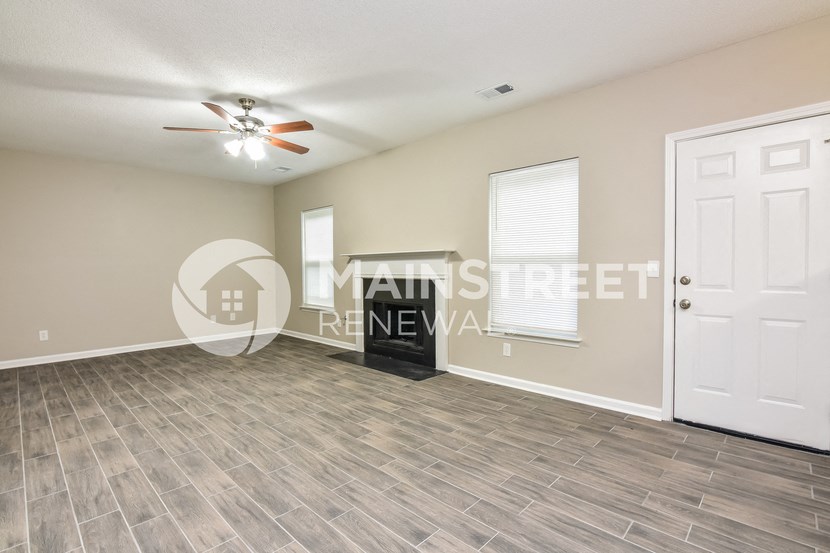 a living room with a white door and a ceiling fan
