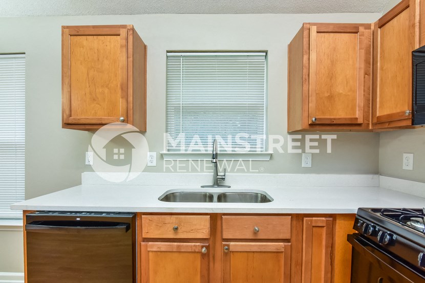 a kitchen with wood cabinets and a sink and a window