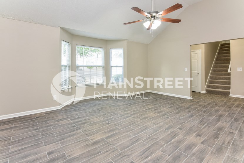 a living room with a staircase and a ceiling fan
