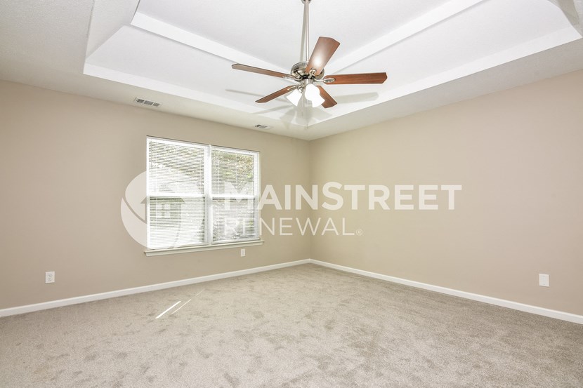 an empty living room with a ceiling fan and a window