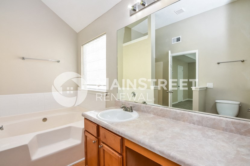 a bathroom with a large mirror and a sink and a bath tub