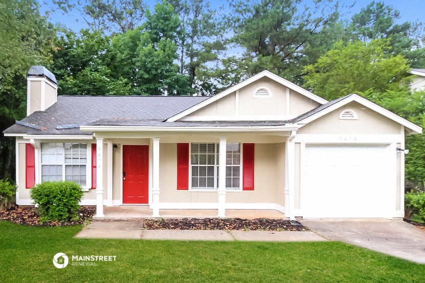 a white house with a red door and a lawn