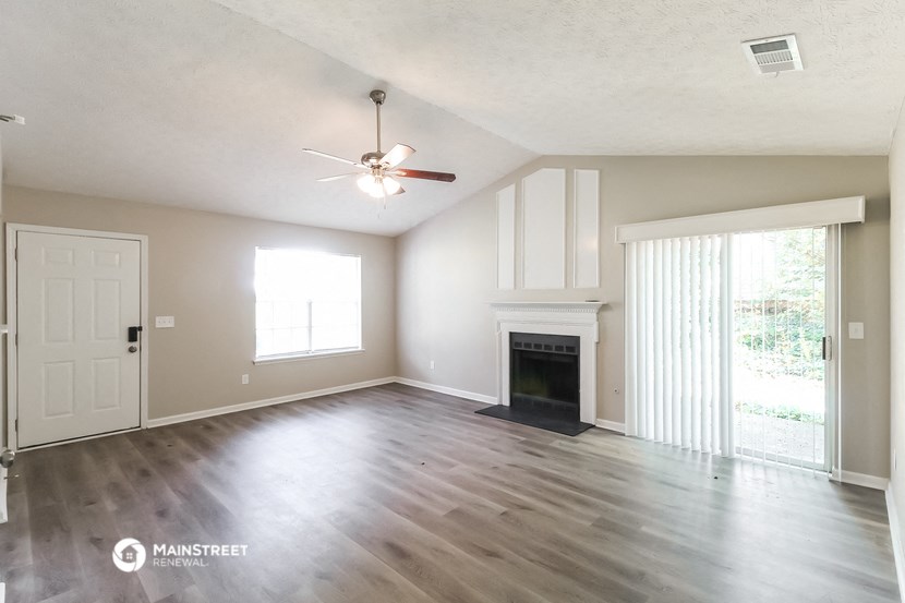 an empty living room with a fireplace and a ceiling fan