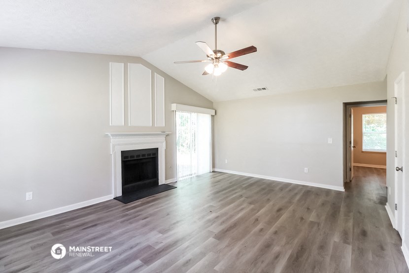 a living room with a fireplace and a ceiling fan
