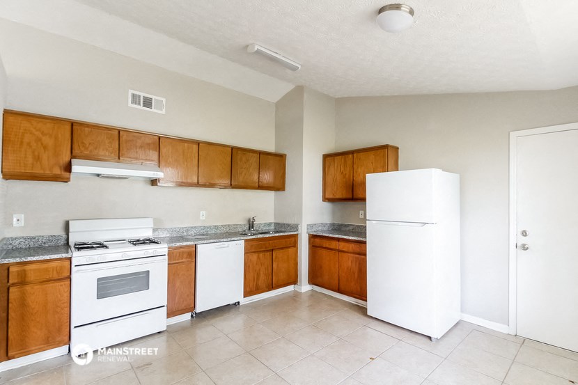an empty kitchen with white appliances and wooden cabinets