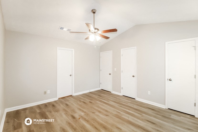 a bedroom with white walls and wood floors and a ceiling fan