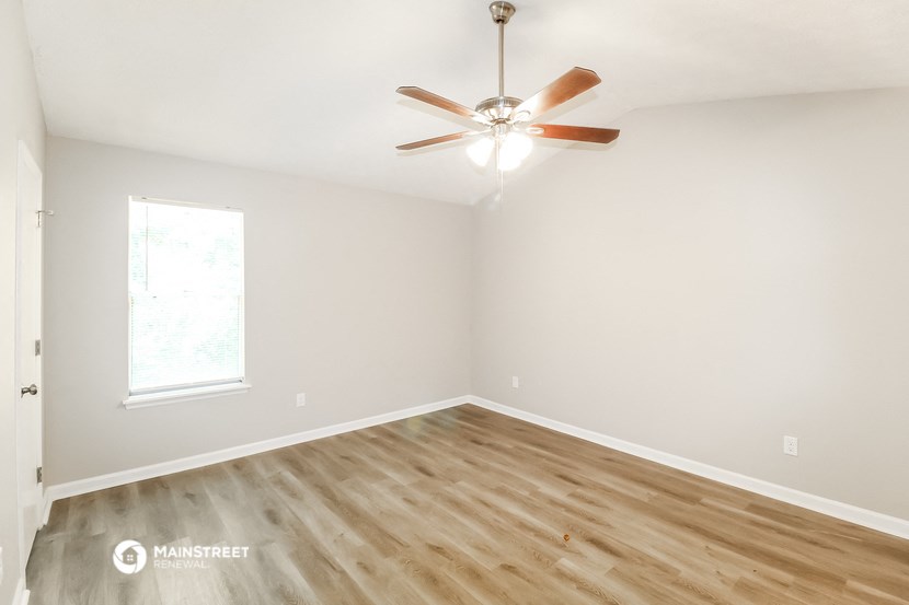 an empty room with wood floors and a ceiling fan
