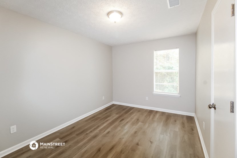 an empty room with wood flooring and a window