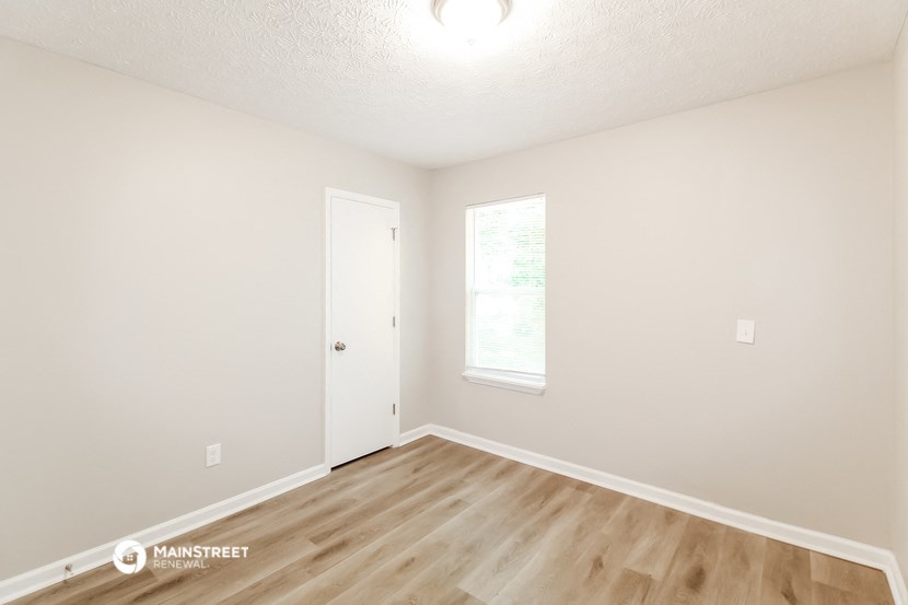 the spacious living room with hardwood flooring and white walls
