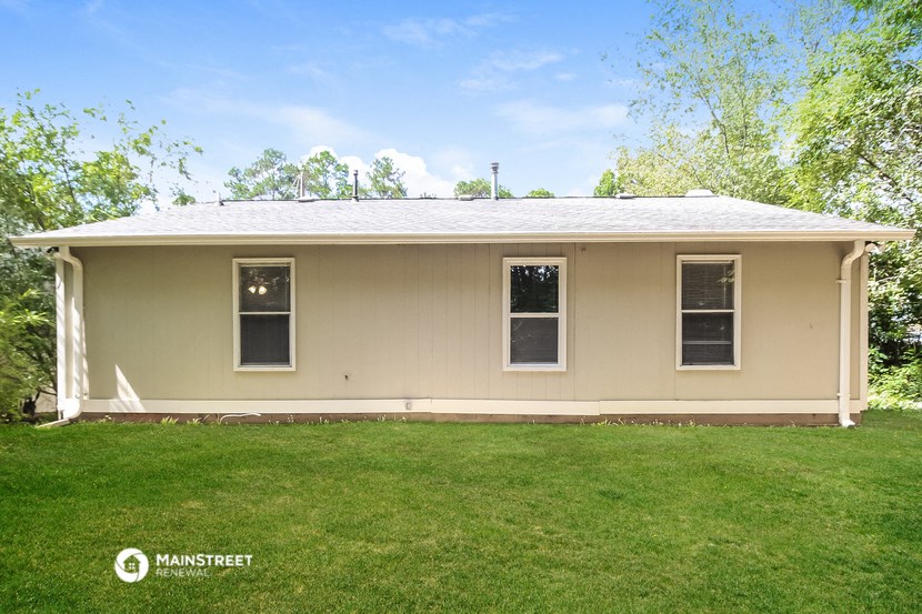 a beige house with a lawn and trees