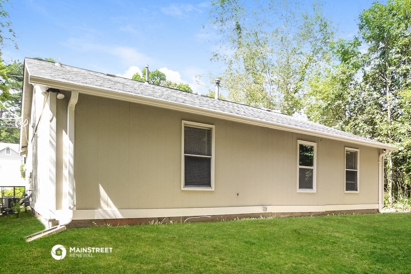 the front of a yellow house with a lawn and trees