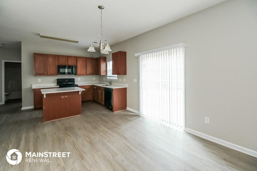 a spacious kitchen with wood flooring and a large window