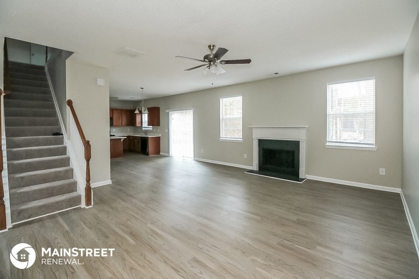 an empty living room with a fireplace and a ceiling fan