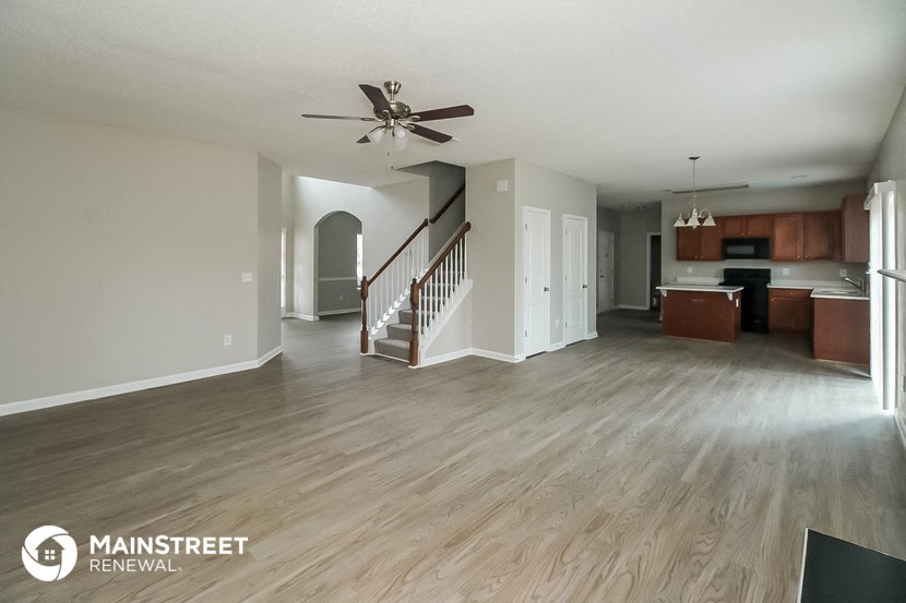 an open living room and kitchen with wood flooring and a ceiling fan