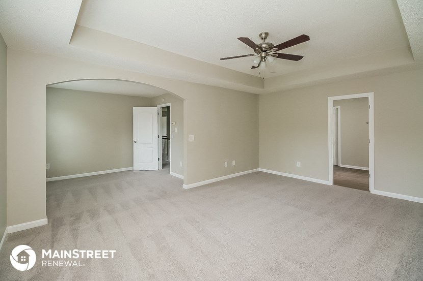 an empty living room with a ceiling fan