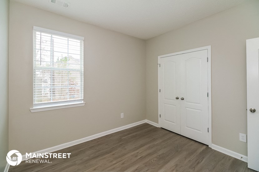 the living room of an apartment with a door and a window