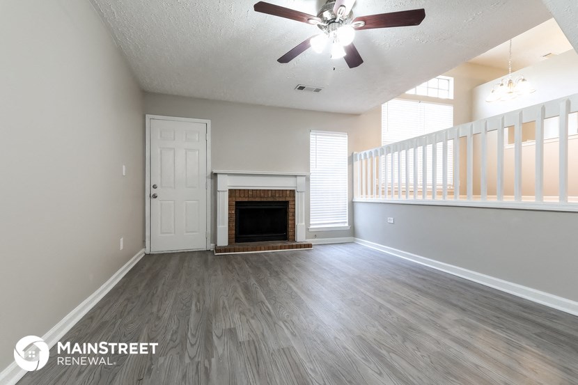 an empty living room with a fireplace and a ceiling fan