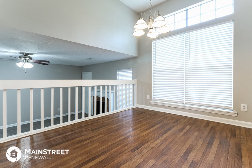 an empty living room with a white railing and a large window