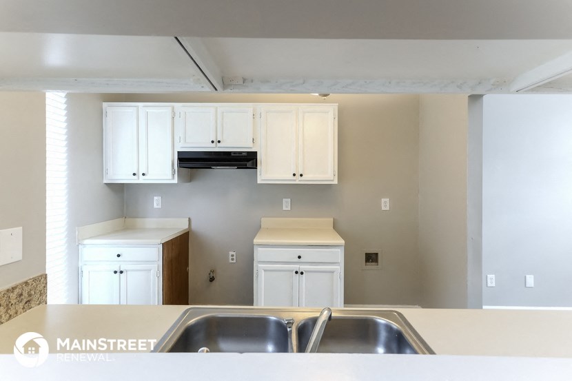 an empty kitchen with white cabinets and a sink