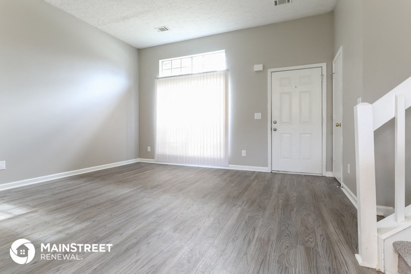 the living room of a new home with wood floors and a white door