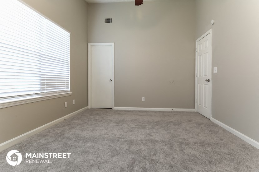 a carpeted room with a large window and a door