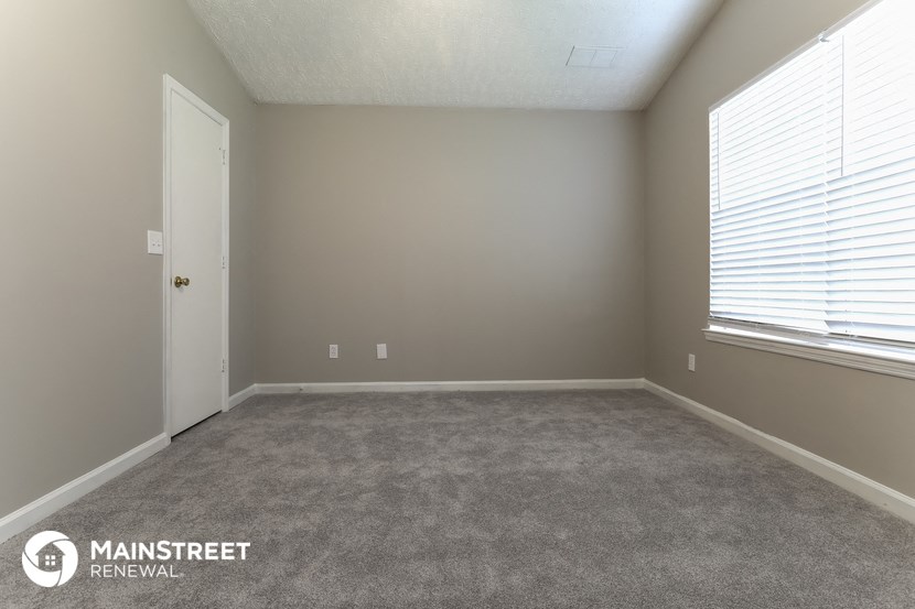 a carpeted room with a large window and a door