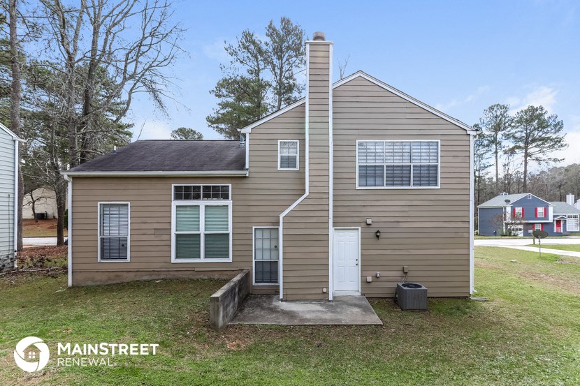 the front of a tan house with a white door