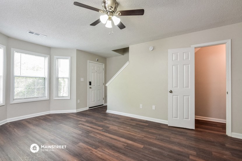 the living room of an empty house with a ceiling fan