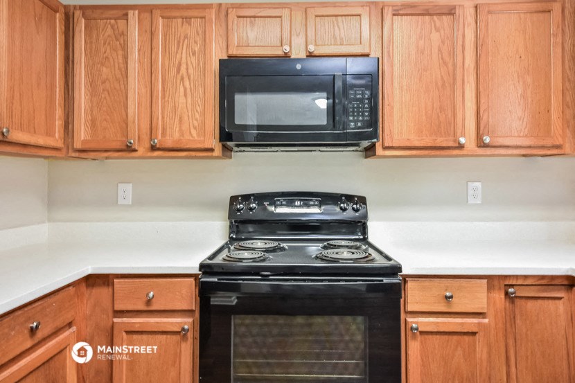 a kitchen with wood cabinets and a black stove and a microwave