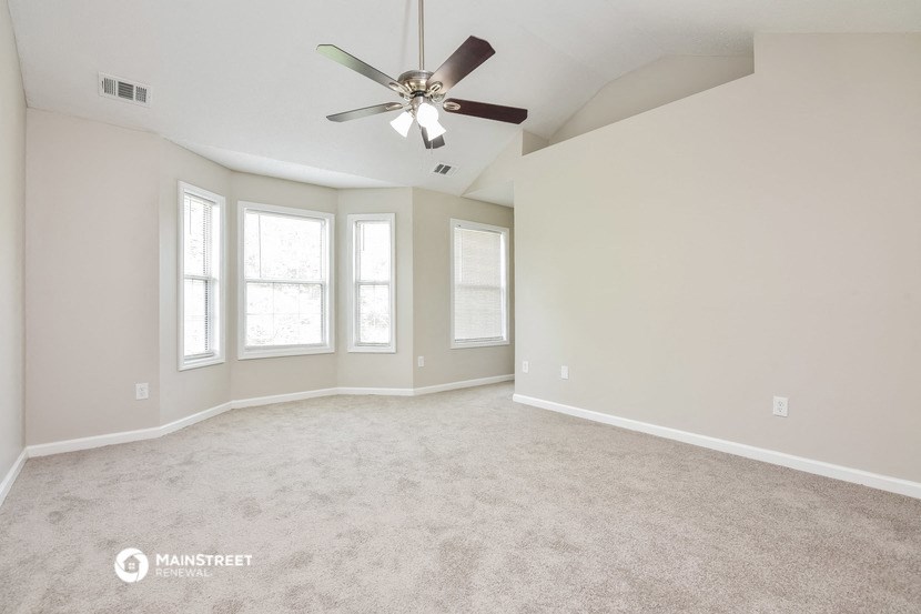 an empty living room with a ceiling fan and windows
