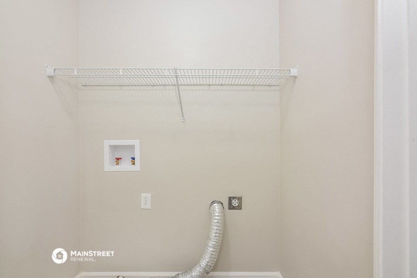 a white bathroom with a pipe and a shelf on the wall