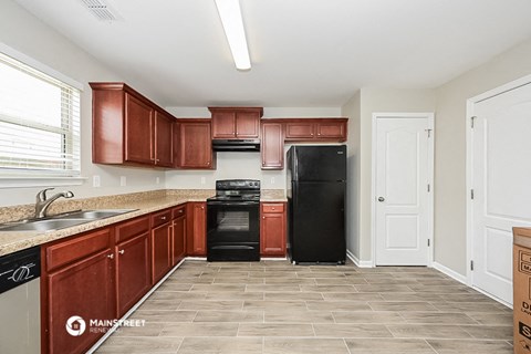 a kitchen with wooden cabinets and a black refrigerator