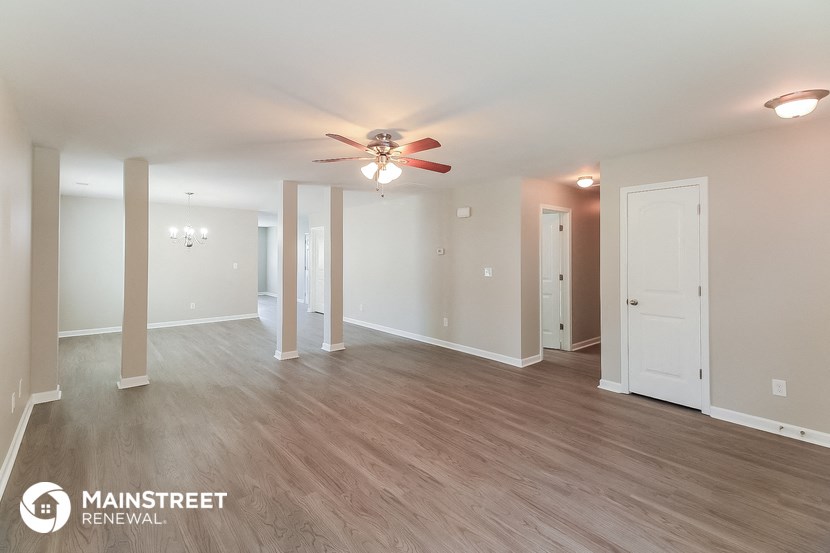 an empty living room with a ceiling fan and wood flooring