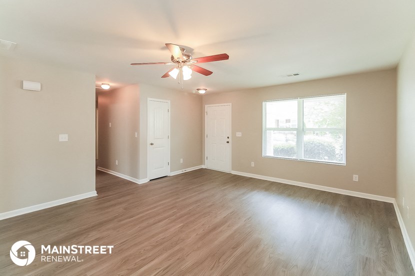 the living room of an empty house with a ceiling fan