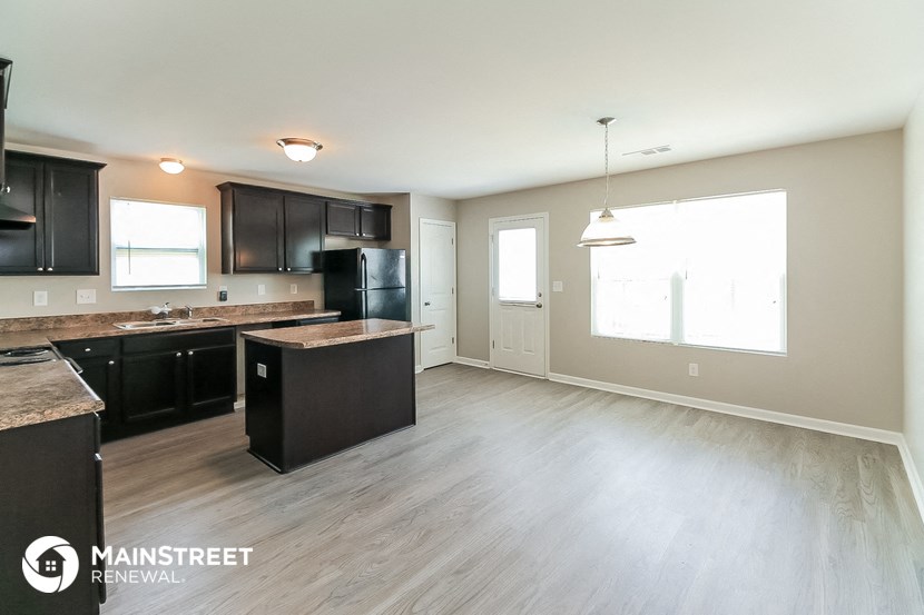 an empty kitchen with black appliances and wood flooring