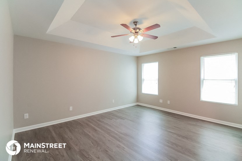 the spacious living room with ceiling fan and wood flooring