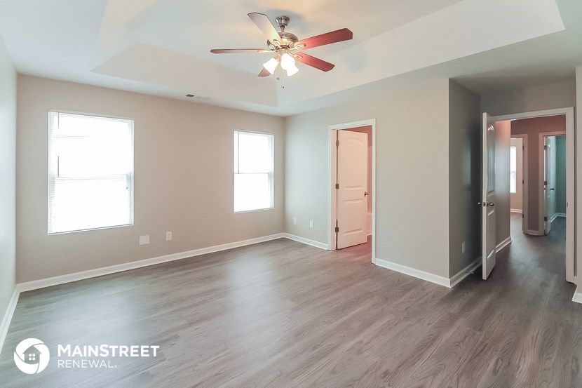 an empty living room with wood floors and a ceiling fan